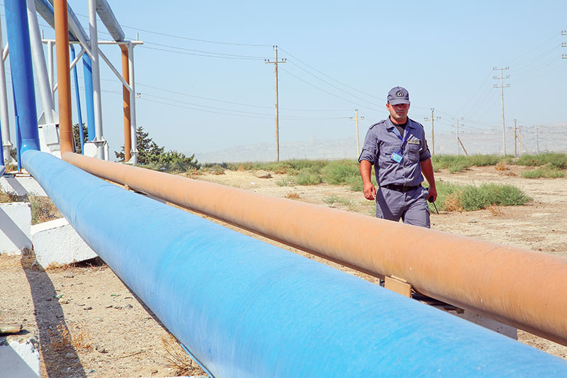Security staff outside an oil plant checks a pipeline.  